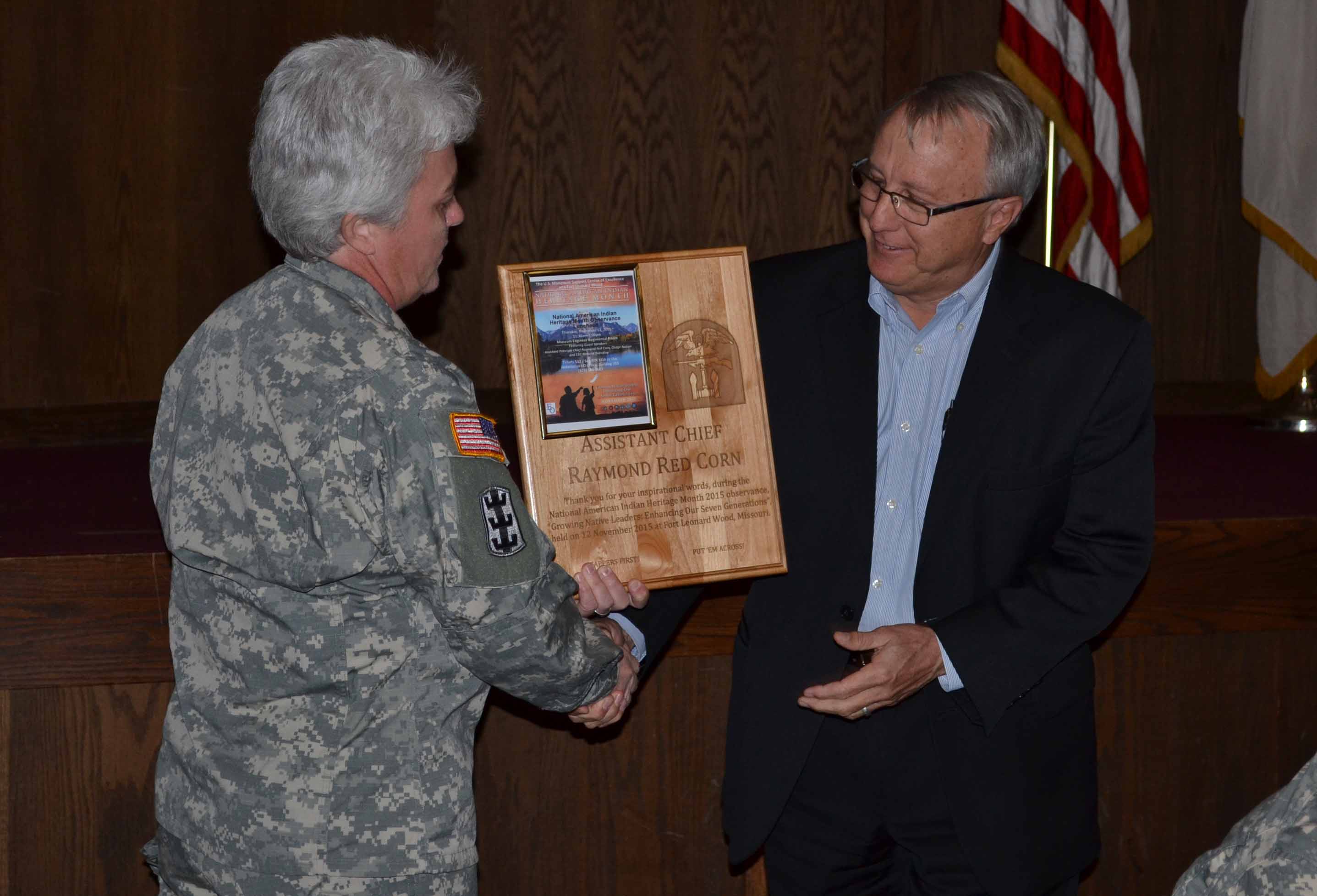 Assistant Chief Raymond Red Corn receives a plaque from COL. Heather Warden for speaking at the base's Native American Heritage Celebration.