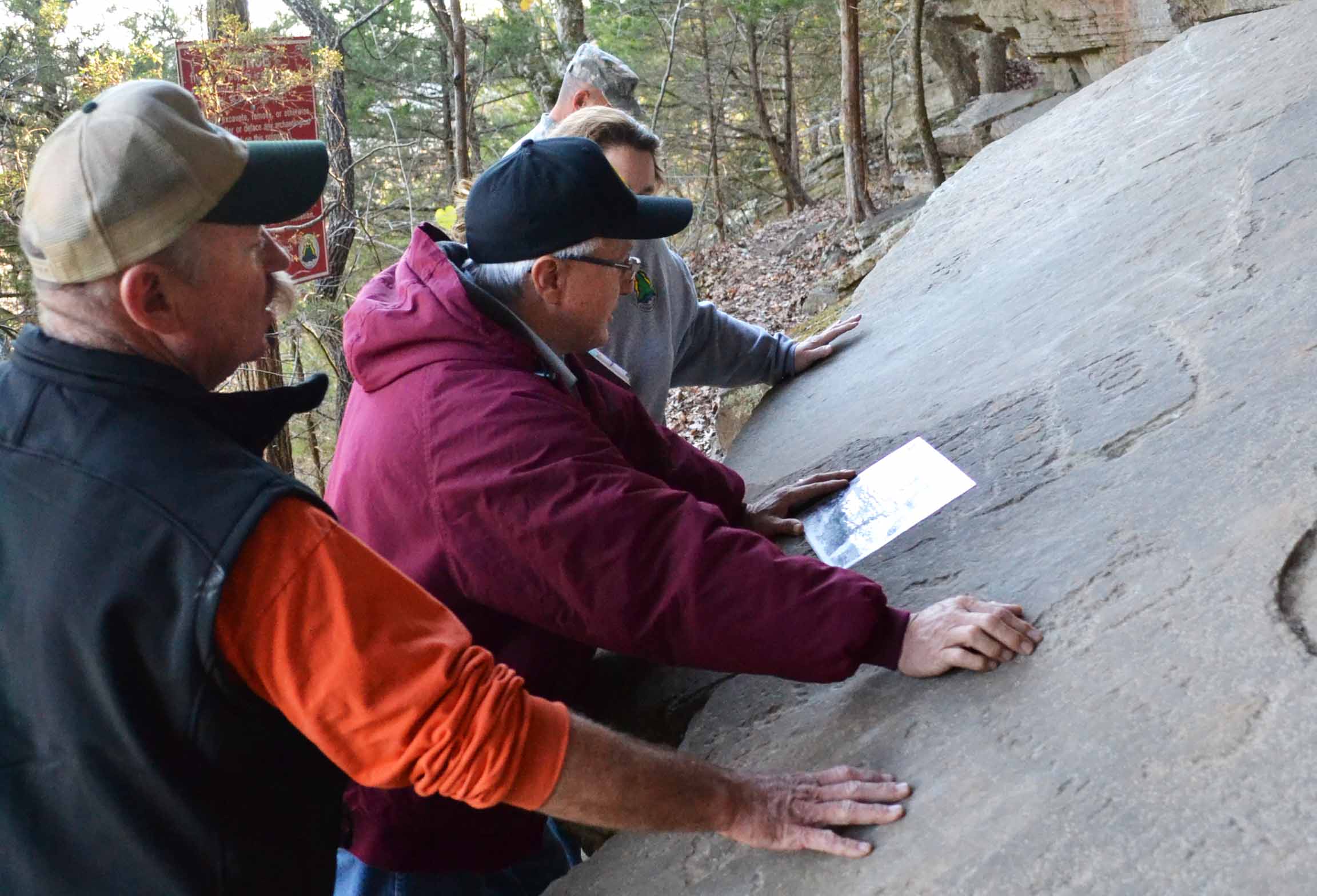 Assistant Chief Raymond Red Corn compares a 1960's photo of the same rock art and the remaining rock art after decades of vandalism and theft.
